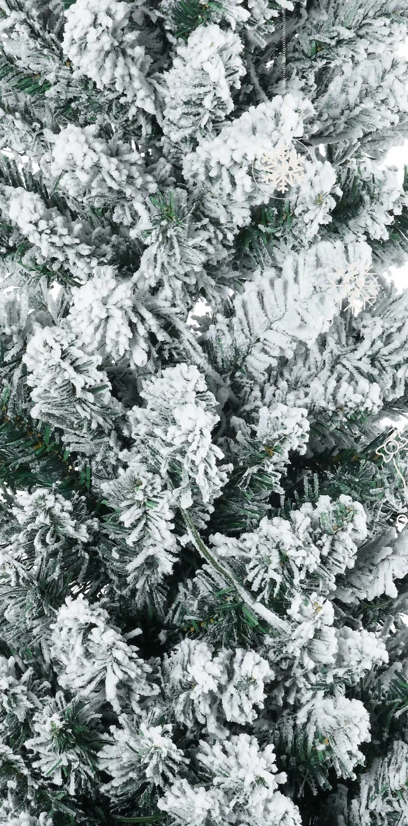 Smalt snødekt juletre med varmhvite lys i stue